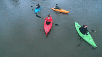A Man In A Red Kayak Is Paddling Next To Two Other Kayaks GIF