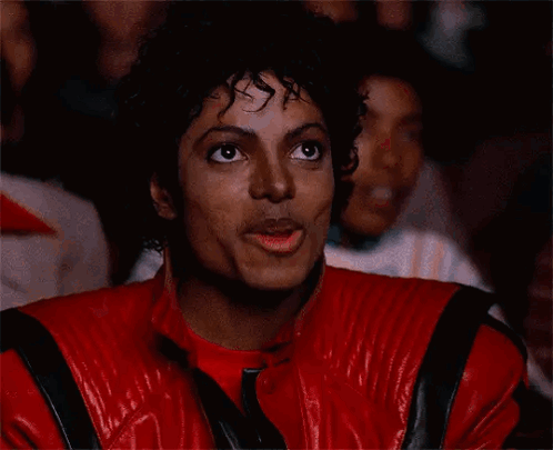 A Man In A Red Leather Jacket Is Covering His Mouth GIF