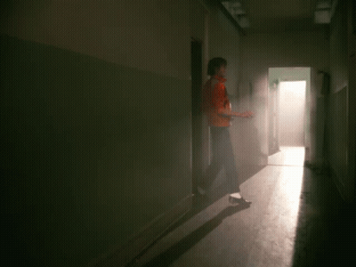 A Man In A Red Leather Jacket Is Standing In A Hallway GIF