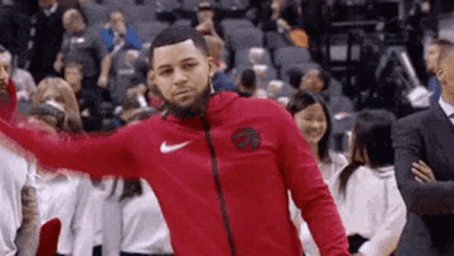 A Man In A Red Nike Jacket Is Standing On A Basketball Court In Front Of A Crowd . GIF