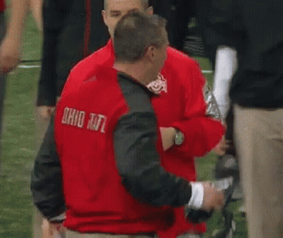 A Man In A Red Nike Jacket Is Talking To Another Man In A Green Shirt . GIF