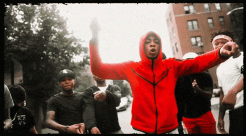 A Man In A Red Nike Jacket Stands In A Crowd Of People GIF