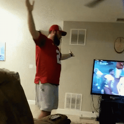 A Man In A Red Number 2 Jersey Stands In Front Of A Tv GIF