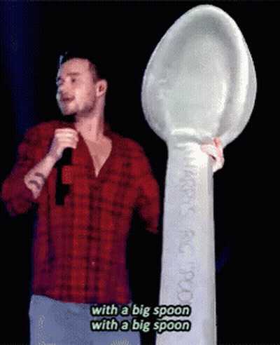 A Man In A Red Plaid Shirt Is Holding A Microphone And A Big Spoon GIF