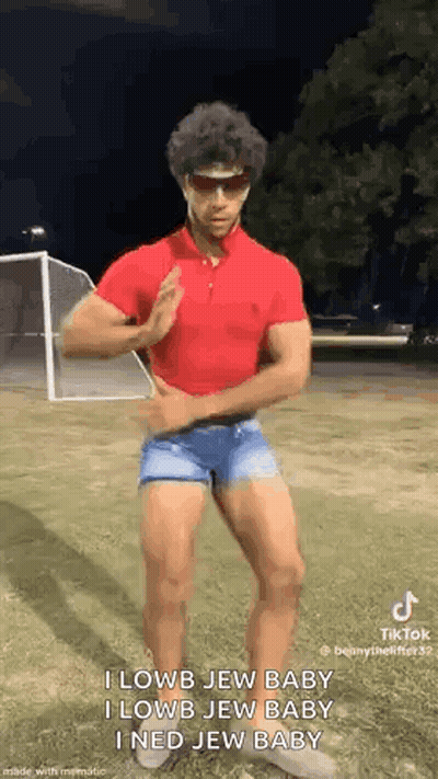A Man In A Red Polo Shirt And Blue Shorts Is Dancing In A Field . GIF