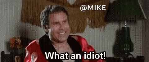 A Man In A Red Robe Is Sitting In A Chair And Smiling While Saying What An Idiot . GIF