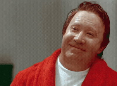 A Man In A Red Robe Is Smiling And Looking At The Camera GIF