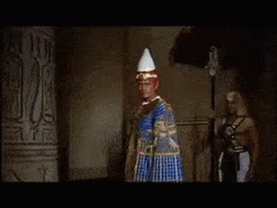A Man In A Red Robe Is Standing Next To A Woman In A Gold Dress GIF
