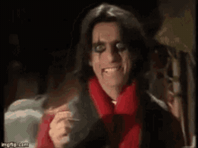 A Man In A Red Scarf Is Smiling And Holding A Cigarette . GIF