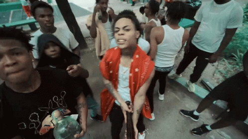 A Man In A Red Scarf Is Surrounded By A Group Of People GIF