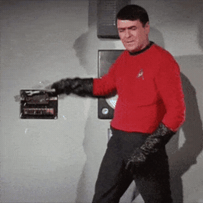 A Man In A Red Shirt And Black Gloves Is Standing In Front Of A Door GIF