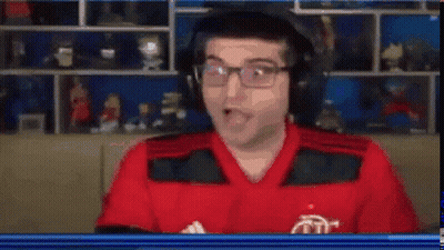 A Man In A Red Shirt And Black Vest Is Looking At The Camera With His Mouth Open . GIF
