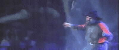 A Man In A Red Shirt And Blue Jeans Is Dancing On A Stage . GIF