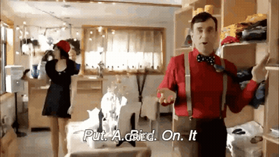 A Man In A Red Shirt And Suspenders Is Standing In A Room With A Woman In A Black Dress . GIF