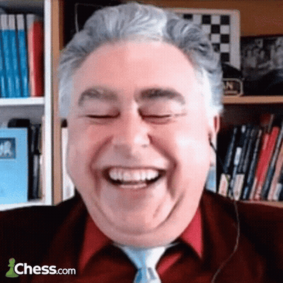 A Man In A Red Shirt And Tie Is Smiling In Front Of A Bookshelf With Chess.com Written On The Bottom GIF