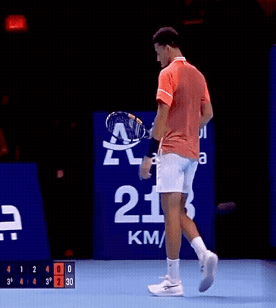 A Man In A Red Shirt And White Shorts Is Holding A Tennis Racquet GIF