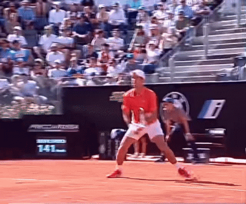 A Man In A Red Shirt And White Shorts Is Playing Tennis On A Court GIF