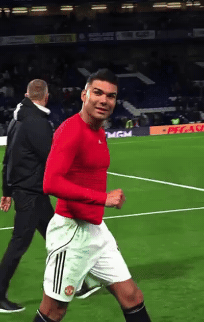 A Man In A Red Shirt And White Shorts Is Running On A Field GIF