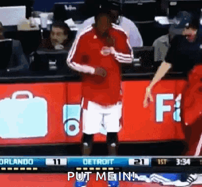 A Man In A Red Shirt And White Shorts Is Standing On A Basketball Court . GIF