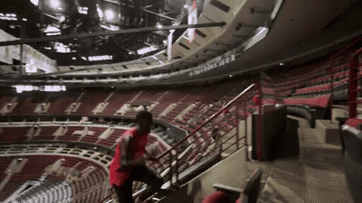 A Man In A Red Shirt Climbs The Stairs Of A Stadium GIF
