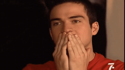 A Man In A Red Shirt Covering His Mouth With His Hands GIF