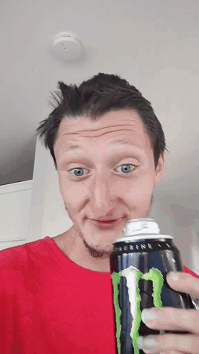 A Man In A Red Shirt Holds A Can Of Monster Energy Drink GIF