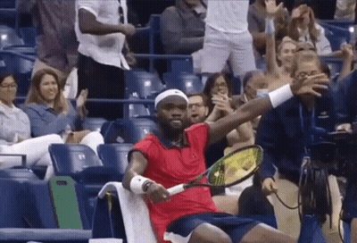 A Man In A Red Shirt Holds A Tennis Racquet In Front Of A Crowd GIF