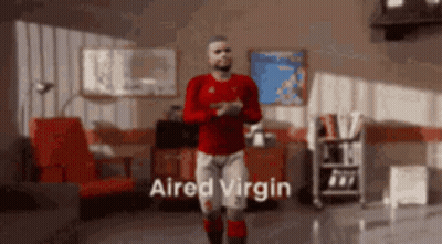 A Man In A Red Shirt Is Dancing In A Living Room With The Words " Aired Virgin " Written On The Bottom GIF