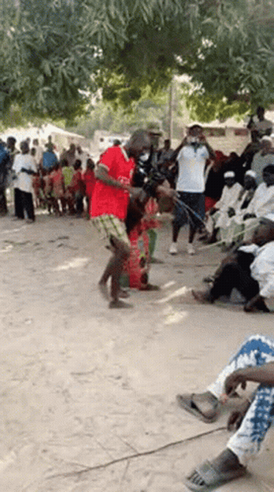 A Man In A Red Shirt Is Dancing In Front Of A Crowd . GIF