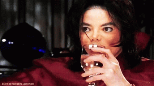 A Man In A Red Shirt Is Drinking From A Wine Glass With The Words Loveformichael Jackson Below Him GIF