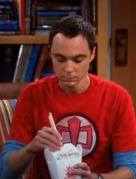 A Man In A Red Shirt Is Eating From A Container With Chopsticks GIF