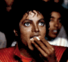 A Man In A Red Shirt Is Eating Something With His Hands GIF