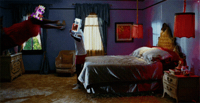 A Man In A Red Shirt Is Flying Through The Air While Holding A Game Controller In A Bedroom GIF