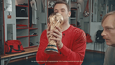 A Man In A Red Shirt Is Holding A Gold Trophy GIF
