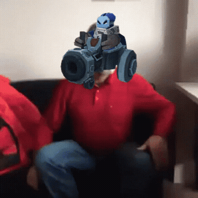 A Man In A Red Shirt Is Holding A Gun In Front Of His Head GIF