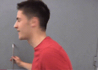 A Man In A Red Shirt Is Holding A Knife And Looking At The Camera GIF