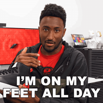 A Man In A Red Shirt Is Holding A Pair Of Shoes And Says I 'M On My Feet All Day GIF