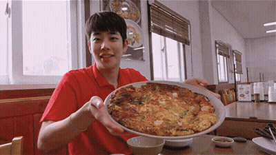 A Man In A Red Shirt Is Holding A Plate Of Food In His Hands GIF