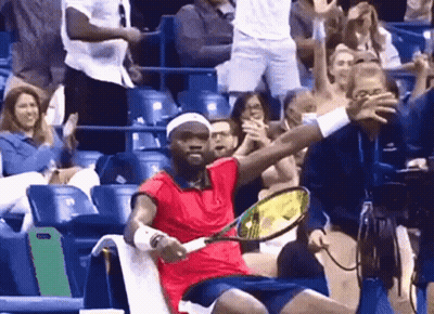 A Man In A Red Shirt Is Holding A Tennis Racquet In Front Of A Crowd GIF