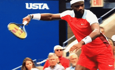 A Man In A Red Shirt Is Holding A Tennis Racquet In Front Of A Sign That Says Usta GIF
