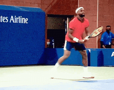 A Man In A Red Shirt Is Holding A Tennis Racquet On A Tennis Court In Front Of A Tes Airline Sign GIF