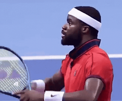 A Man In A Red Shirt Is Holding A Tennis Racquet On A Tennis Court . GIF