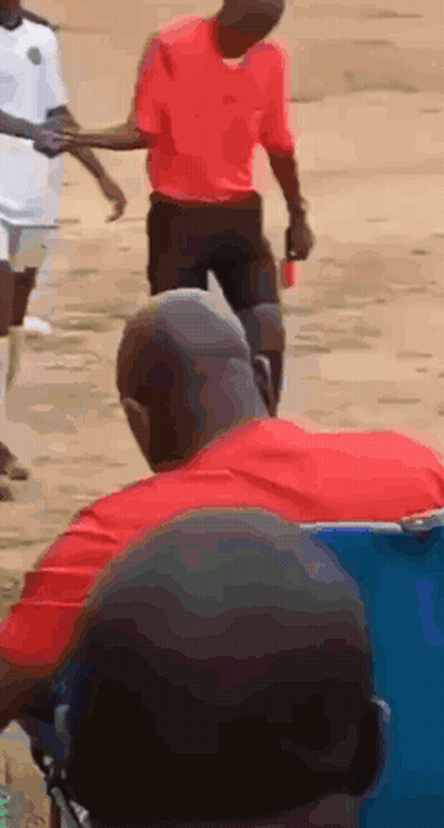 A Man In A Red Shirt Is Holding Another Man 'S Hand While Walking GIF