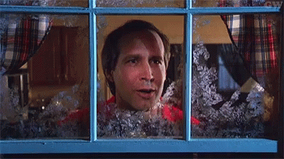 A Man In A Red Shirt Is Looking Out Of A Window With Snow On It . GIF