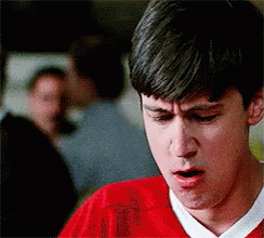 A Man In A Red Shirt Is Making A Funny Face While Looking Down . GIF