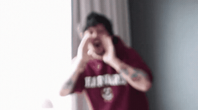 A Man In A Red Shirt Is Making A Heart Shape With His Hands In Front Of His Face . GIF