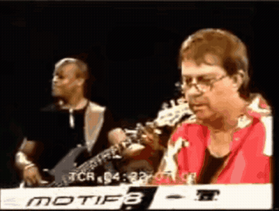 A Man In A Red Shirt Is Playing A Keyboard With Motif8 Written On It GIF