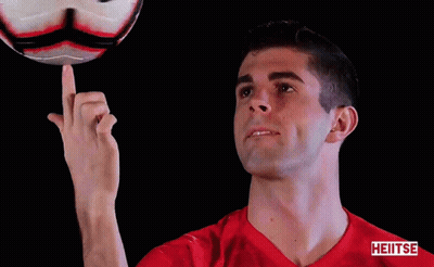 a man in a red shirt is pointing at a soccer ball with the word heiiiise on the bottom