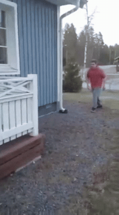 A Man In A Red Shirt Is Running In Front Of A Blue Building GIF