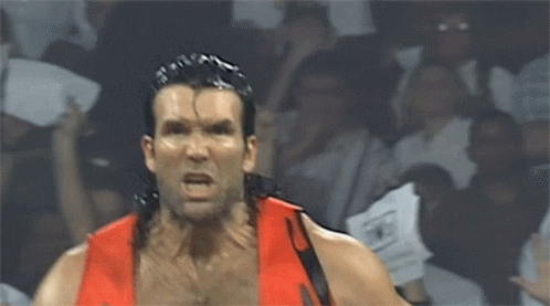 A Man In A Red Shirt Is Screaming In Front Of A Crowd With Nwo Signs GIF